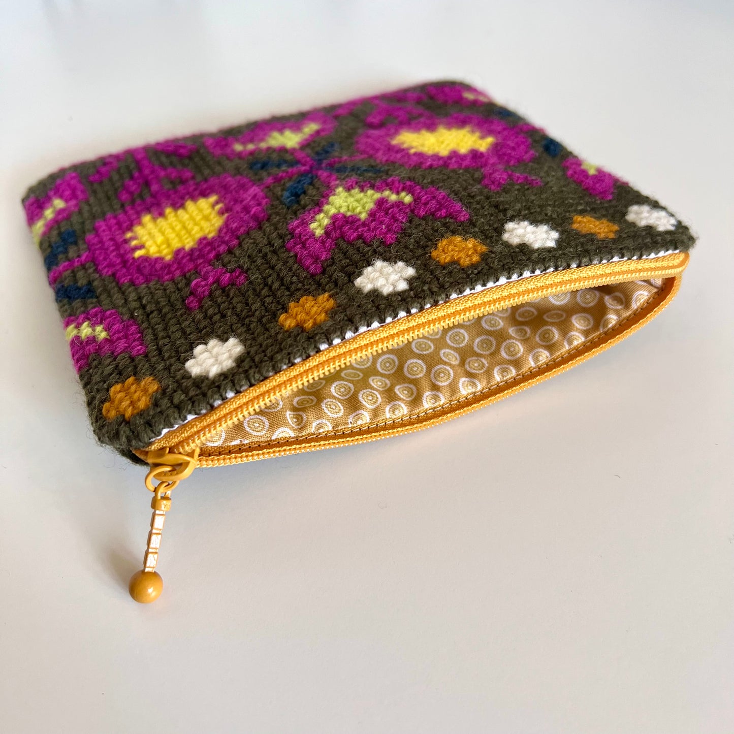 Handgjord unik börs korsstygn broderi i retrostil broderad i ull med blommor och blad m, färger mörkgrön gul mörkt rosa orange vit mönster är från svensk hemslöjd insida beige med vita prickar och är bomull 