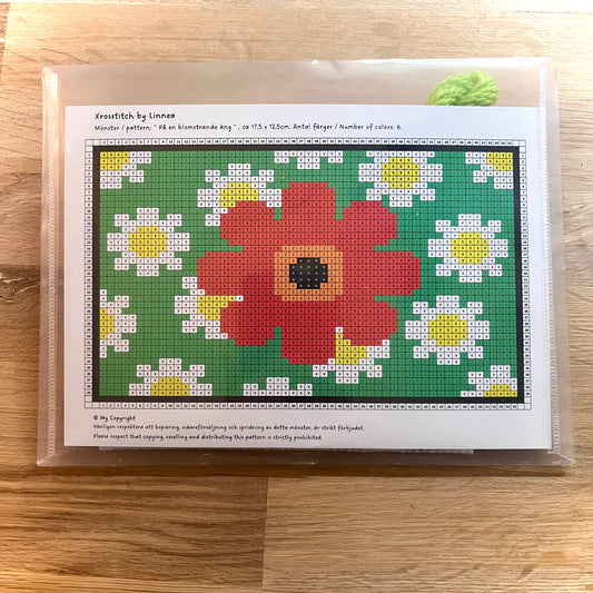 Broderikit med ullgarn på en blomstrande äng